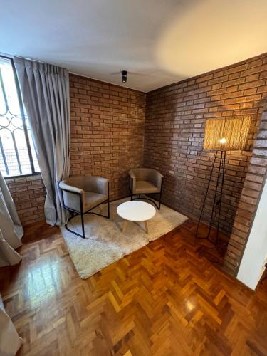 门多萨CASA ALMA LUXURY HOME的一间设有两把椅子和一张桌子的房间,以及砖墙