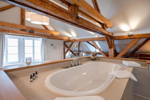OberdorfHotel Weissenstein的设有一个大型白色浴缸,位于带木制天花板的房间内