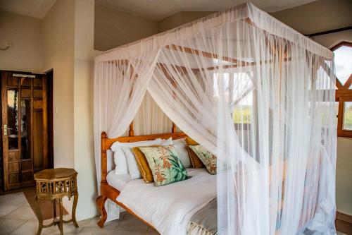基利菲Amani House的卧室配有带白色窗帘的天蓬床