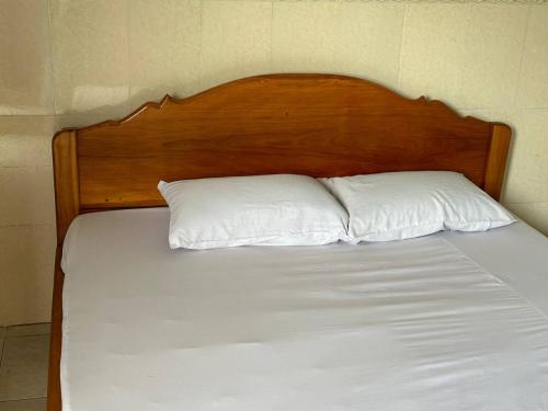 马德望Palm Tree Quest House的一张带木制床头板和两个白色枕头的床
