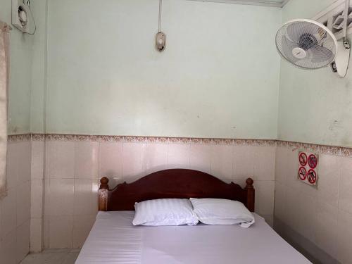 马德望Palm Tree Quest House的一间卧室配有一张带两个枕头的床和风扇