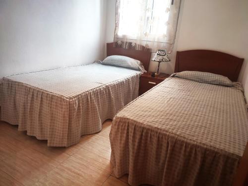 奥罗佩萨德尔马APCOSTAS Playa Coral - Costa Marfil的一间卧室设有两张床和一张桌子上的台灯。