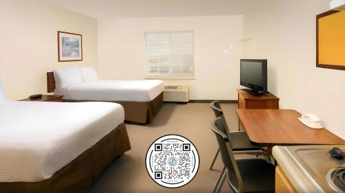 林垦WoodSpring Suites Lincoln Northeast I-80的酒店客房设有两张床、一张桌子和一台电视。