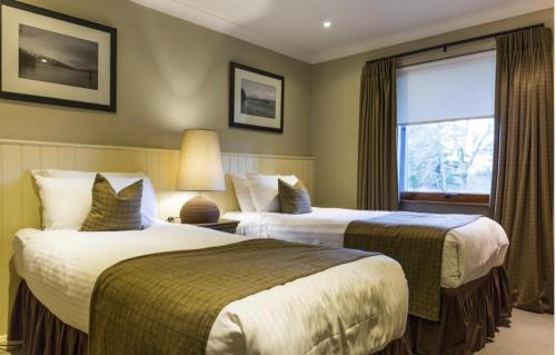 巴洛赫Cameron House - Lodge 17 - Loch Lomond的酒店客房设有两张床和窗户。