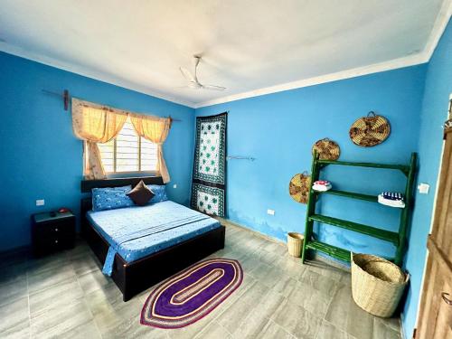 KibweniMama's House的一间拥有蓝色墙壁的卧室、一张床和一个架子