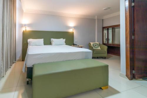 戈亚尼亚Umuarama Plaza Hotel by Castelo Itaipava的一间卧室配有一张大床和一把椅子