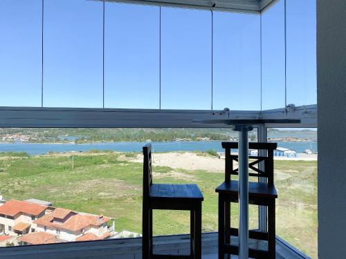 拉古纳Resid. Clube Mar Grosso - Laguna的窗前的一张桌子和两把椅子