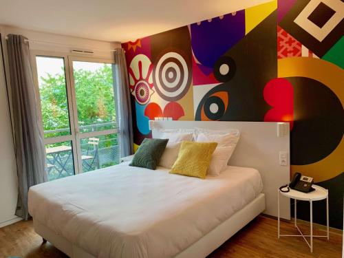 LatresneBrit Hotel Bordeaux Arena的一间卧室设有一张大床和色彩缤纷的墙壁