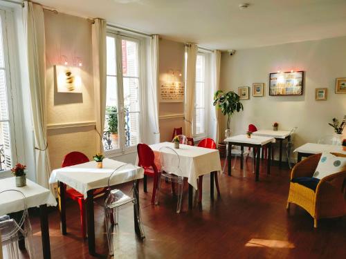 波尔多Brit Hotel Des Grands Hommes - Bordeaux Centre的餐厅设有白色的桌椅和窗户。