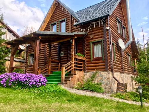 布克维Cottage PolyaNitsa окремий котедж з каміном的小木屋前方有紫色花