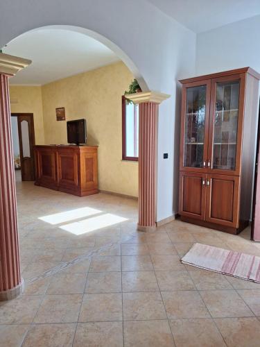 IrgoliCasa vacanze Irgoli的客厅设有拱门、木柜和电视。