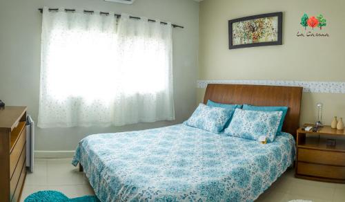 蒂巴吉Pousada La Casona的一间卧室配有一张带蓝色棉被的床和窗户。
