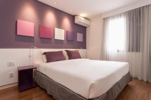 圣保罗Paulista Suites by Charlie的卧室设有一张白色大床和一扇窗户。
