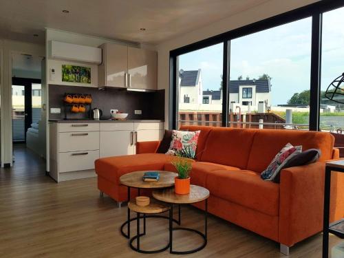 佩讷明德Hausboot Marama - LP10的一间带橙色沙发的客厅和一间厨房