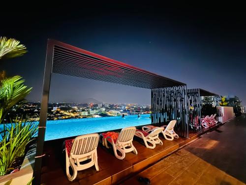 怡保Ipoh Horizon Skypool Town Suites 4-11pax by IWH Suites的一个带椅子的甲板和晚上的游泳池