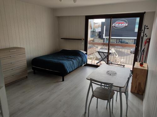 达克斯Studio proche centre-ville的一间卧室配有一张床、一张桌子和一个窗户。