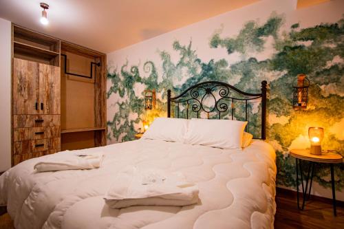 库斯科INYAWASI APARTMENT的卧室配有一张大床,墙上挂有绘画作品