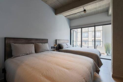 墨西哥城P302 Zocalo 3bdrm 2bath Rooftop AC的一间卧室设有两张床和大窗户