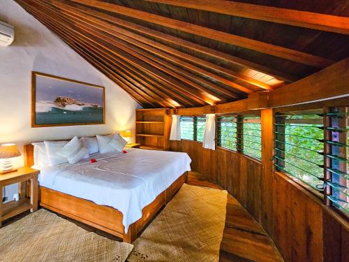内布拉拉Keong Villas的一间带一张床的卧室,位于带木制天花板的房间内
