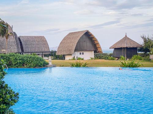 美奈美奈湾度假酒店的一个带游泳池和两个茅草屋顶的度假村