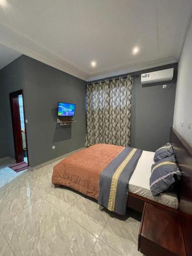雅温得Paradis des anges的一间卧室配有一张床,墙上配有电视