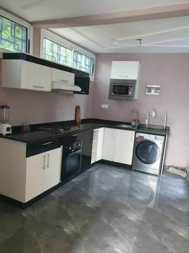 雅温得Paradis des anges的厨房配有白色橱柜、洗衣机和烘干机