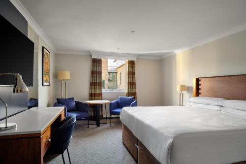 爱丁堡Edinburgh Marriott Hotel Holyrood的酒店客房,配有一张床、一张桌子和椅子