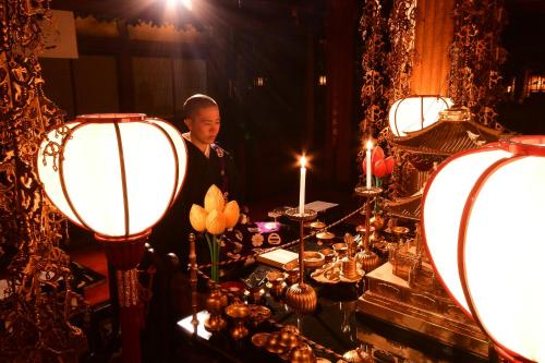 高野山高野山 宿坊 桜池院 -Koyasan Shukubo Yochiin-的站在桌子前的灯光下的人