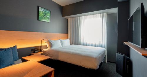 熊本Grids Premium Hotel Kumamoto的酒店客房设有床和窗户。