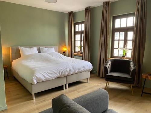 古尔彭Hotel Courage Gulpen-Wittem的一间卧室配有一张床、一把椅子和窗户。