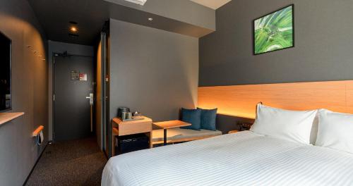 熊本Grids Premium Hotel Kumamoto的酒店客房设有一张大床和一张书桌。