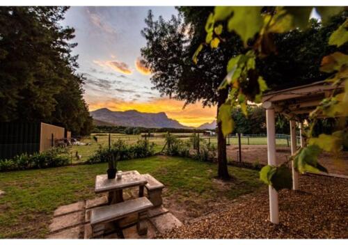 弗朗斯胡克Franschhoek Cottages的庭院里的野餐桌,享有日落美景