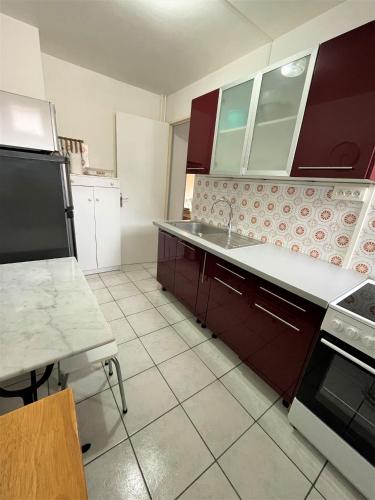 塞尼奥斯Réf 531, Seignosse Océan, Appartement proche de la plage et du centre, 4 personnes的厨房配有红色橱柜和白色瓷砖地板。