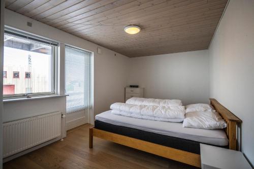 伊卢利萨特4-bedroom house with sea view and hot tub的一间卧室配有一张带白色床单的床和一扇窗户。