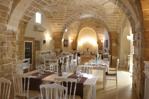 莱切Tenuta Monacelli Lecce的大楼内一家带白色桌椅的餐厅
