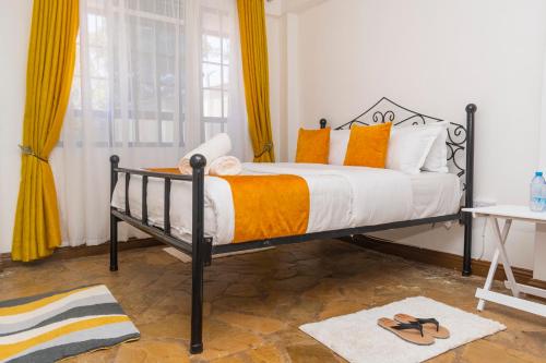 BungomaElevate by African Manor的一间卧室配有带橙色和白色枕头的床