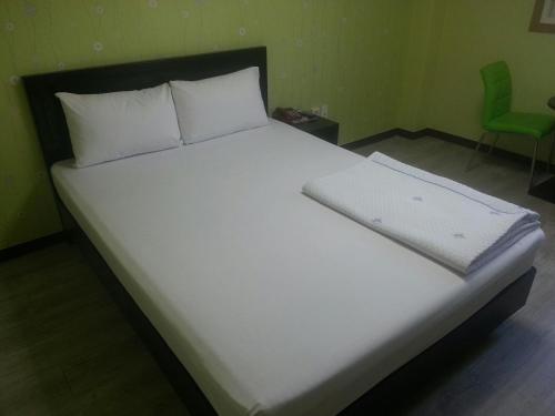 庆州韩松汽车旅馆的一张带白色床单和白色枕头的床