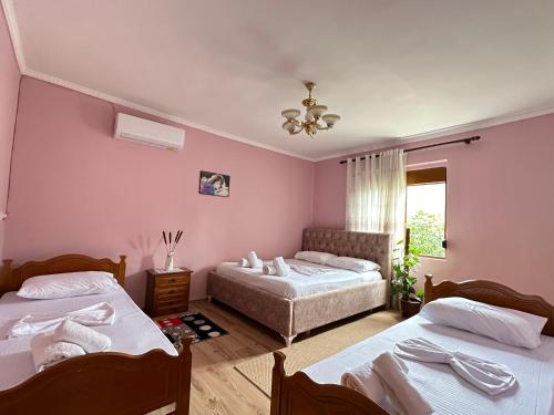 MemaliajVjosa Guest House的配有粉红色墙壁的客房内的两张床