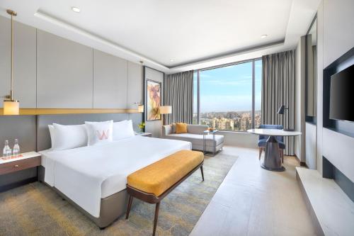 新德里Welcomhotel by ITC Hotels, Dwarka, New Delhi的酒店客房设有一张白色大床和一张沙发。
