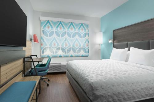 北奥古斯塔Tru By Hilton North Augusta的酒店客房设有一张床、一张书桌和一台电视机。