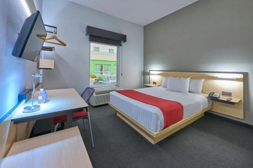 托卢卡都市快捷托卢卡酒店的酒店客房配有一张床和一张带电脑的书桌