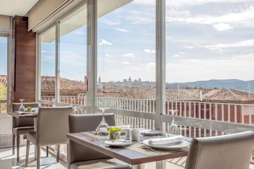 托莱多托莱多欧洲之星酒店的一间带桌椅和大窗户的用餐室