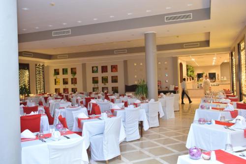 沙姆沙伊赫塔玛拉海滩度假酒店的宴会厅配有白色桌子和红色椅子