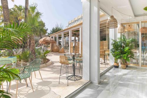 帕尔马诺瓦MarSenses Rosa del Mar Hotel & Spa的一个带桌椅的户外庭院,棕榈树