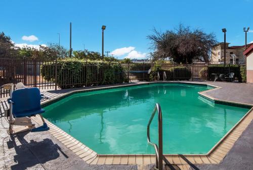 圣安东尼奥HomeTowne Studios by Red Roof San Antonio - SeaWorld Northwest的庭院内带蓝色椅子的游泳池