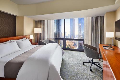 洛杉矶The Westin Bonaventure Hotel & Suites, Los Angeles的酒店客房设有一张大床和一张书桌。