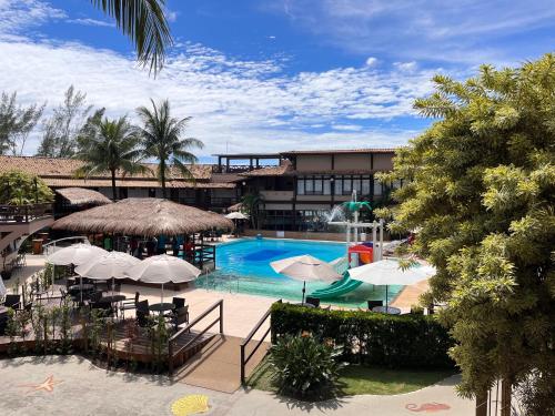 里约达欧特拉斯韦拉欧普拉亚酒店的一个带遮阳伞的游泳池和一个度假村
