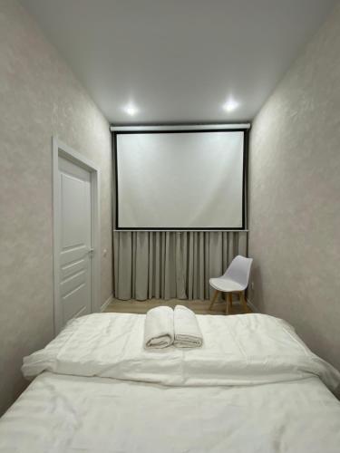阿拉木图Уютный домик для идеального отдыха的卧室配有一张白色大床和一把椅子
