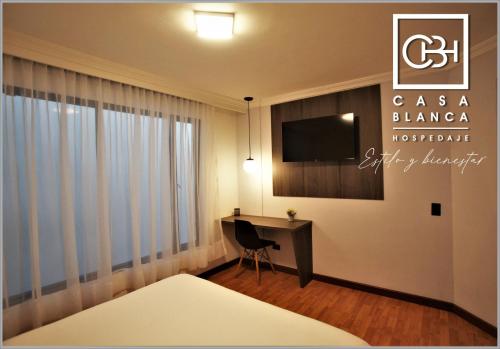 帕斯托Casa Blanca Hospedaje的酒店客房配有书桌和电视。