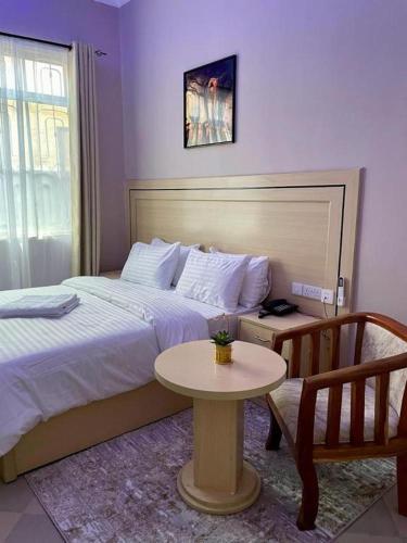 多多马ROSA HOTEL AND APARTMENT - ILAZO的酒店客房配有一张床铺和一张桌子。